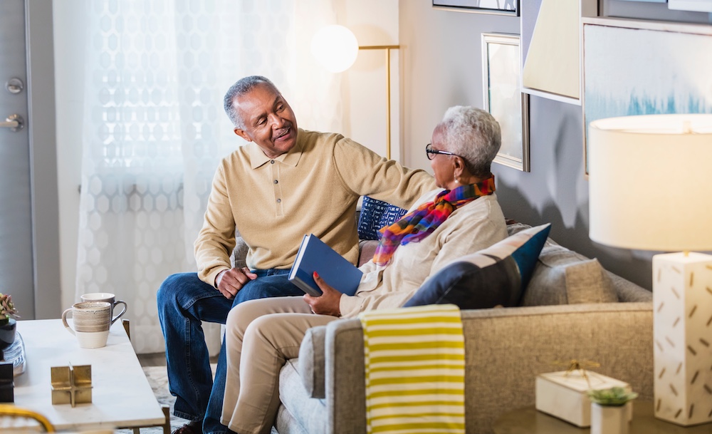 senior couple on couch surrounded by packing boxes.