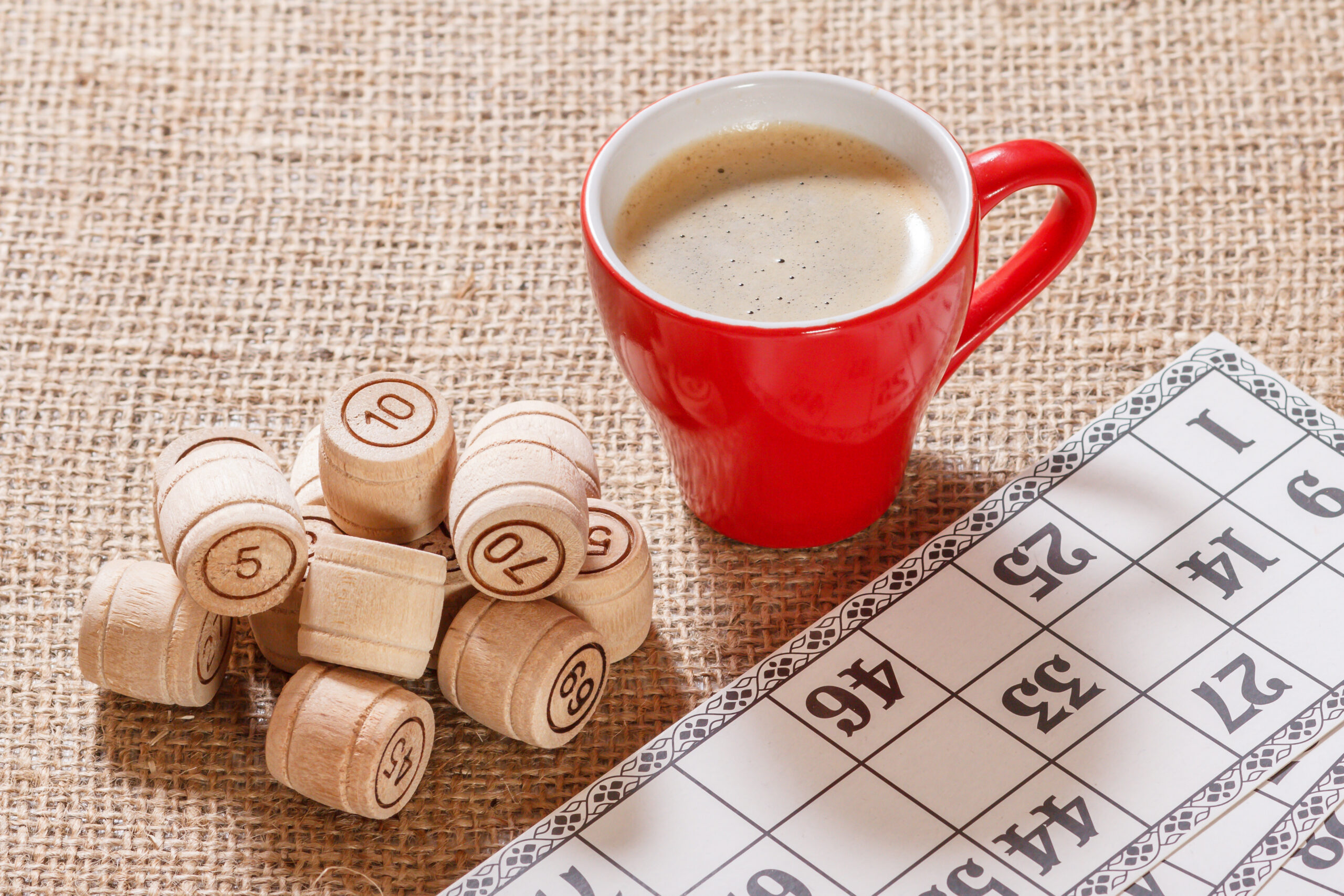 Board game lotto on sackcloth. Wooden lotto barrels and game cards for a game in lotto with cup of coffee