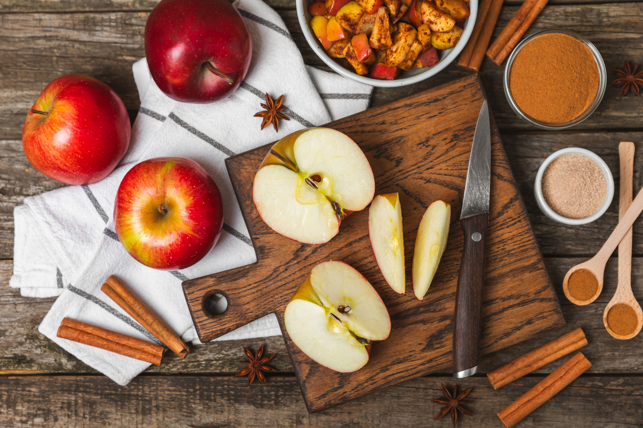Apples with cinnamon on background. Fragrant red spiced apples with cinnamon sticks and star anise. Apple slices with spicy spices. Place for text. Copy space. Harvesting. Fruits.